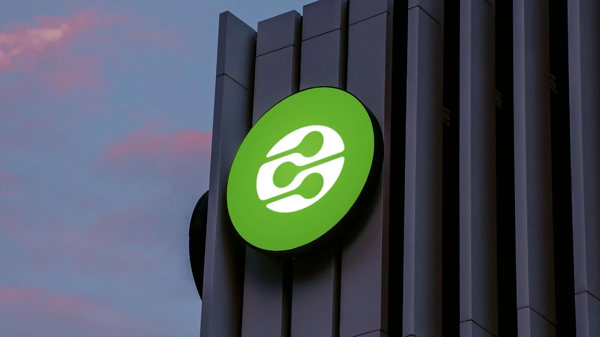 Illuminated round building sign with the white dlna mark on green