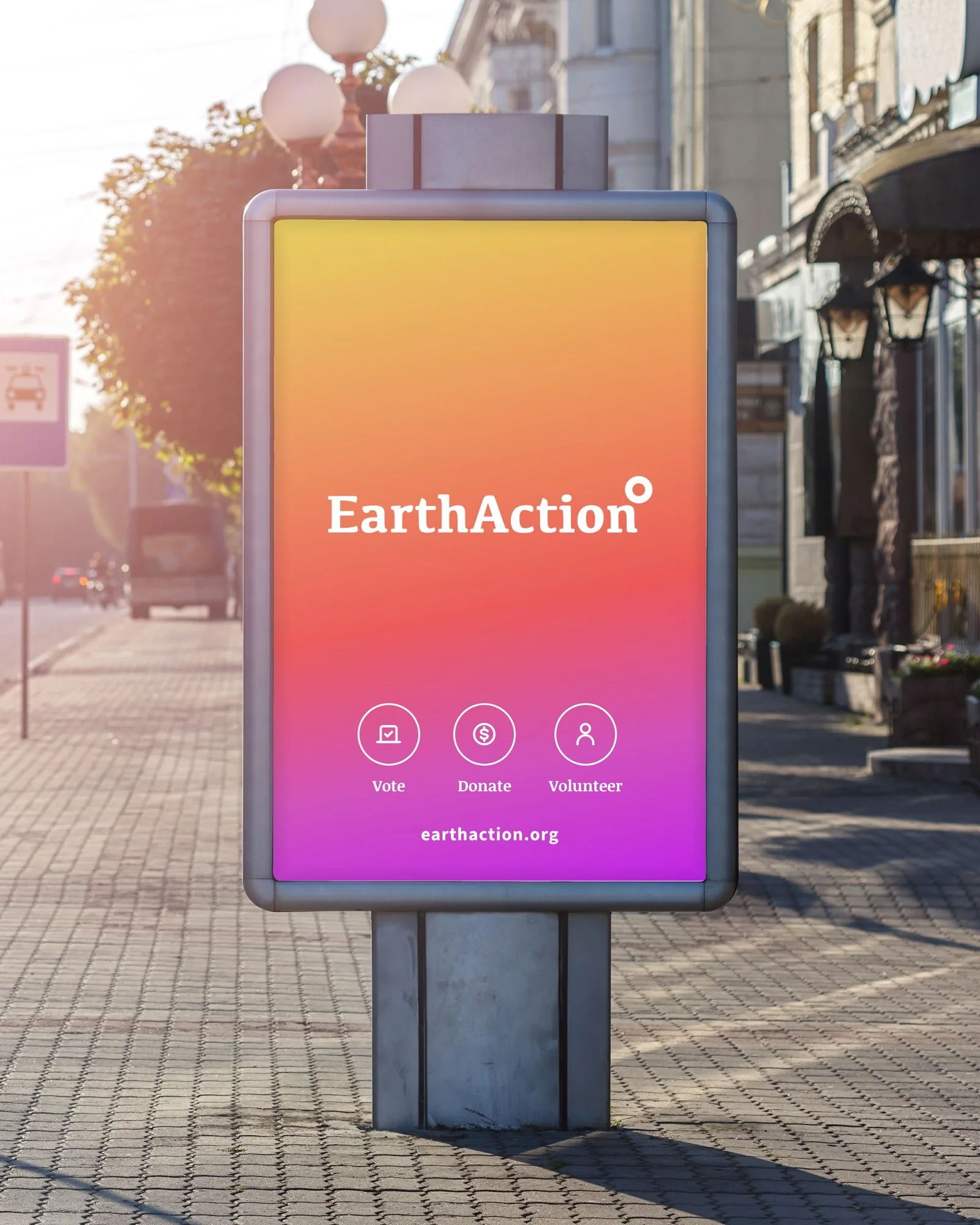 EarthAction street billboard with the scenario gradient, white logo, Vote, Donate and Volunteer icons and earthaction.org