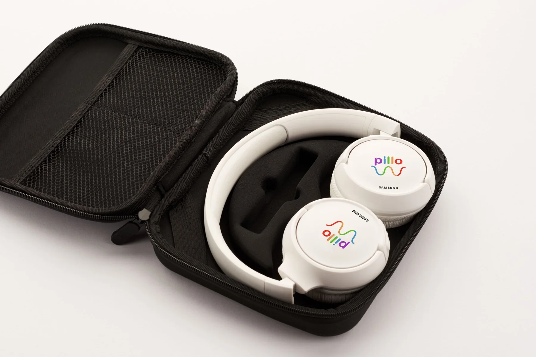 White headphones in an open black case, each ear cup printed with a full-color pillo logo above a small Samsung logo