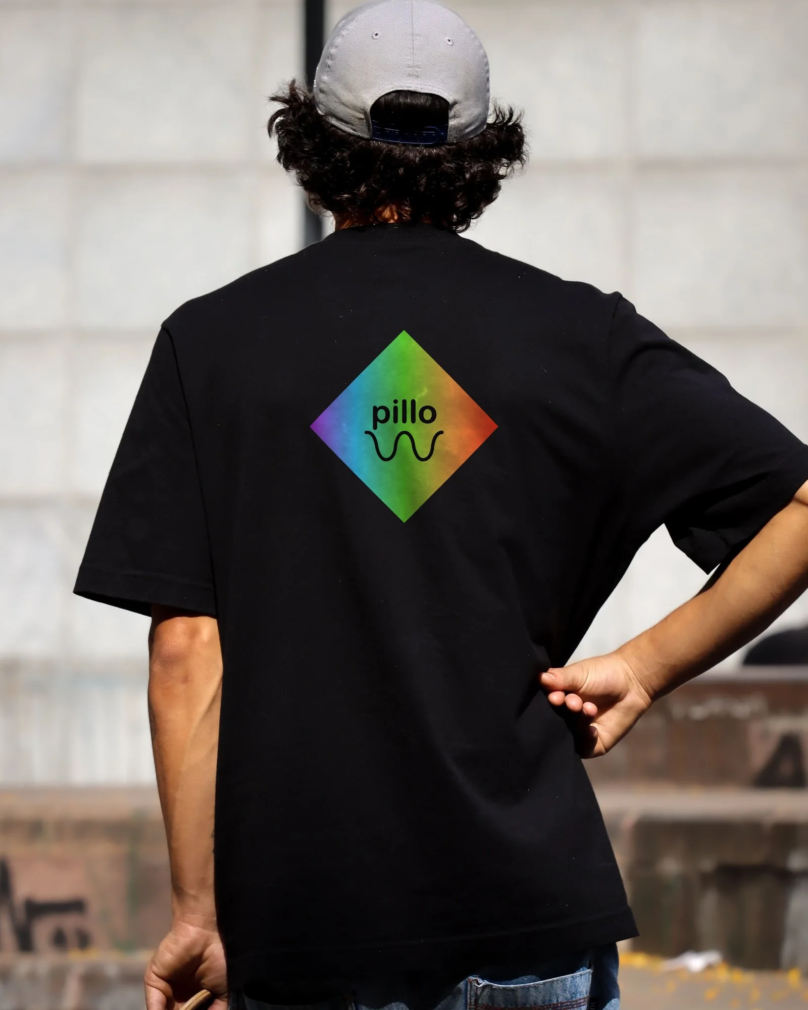 Back of a black T-shirt printed with a pillo spectrum diamond and black pillo logo on the upper back